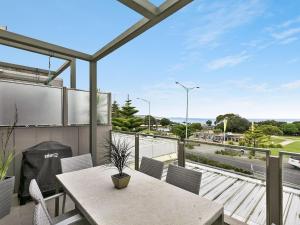 a balcony with a table and chairs and a view of a highway at Waterfront Two in Lorne