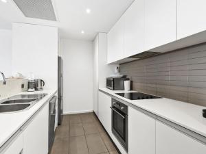 a white kitchen with white cabinets and appliances at Waterfront Two in Lorne