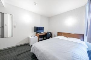 a bedroom with a bed and a desk with a television at Tabist Annex Hotel Tetora Hakodate in Hakodate