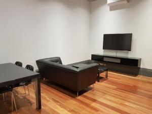 a living room with a black couch and a flat screen tv at Bespoke On Main in Rutherglen