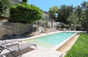 - une piscine avec des chaises longues à côté d'un mur en pierre dans l'établissement Mas des Baussiers, à Saint-Martin-de-Castillon