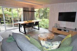 uma sala de estar com um sofá e uma mesa em Wairua Lodge - Rainforest River Retreat em Whitianga