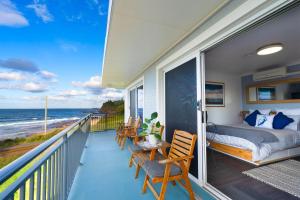 - un balcon avec un lit et des chaises donnant sur l'océan dans l'établissement Sea Breeze Studio, à Kiama