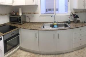 een keuken met een wastafel en een magnetron bij Apartamento primera línea in Denia