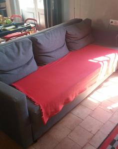 Un sofá con una manta roja. en L'ecole des Filles, en Poncé sur Le Loir