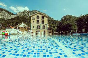 a large swimming pool with a building in the background at Pensiunea JOJO Imperial Resort&Spa in Băile Herculane