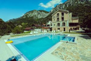 une grande piscine en face d'un bâtiment avec une montagne dans l'établissement Pensiunea JOJO Imperial Resort&Spa, à Băile Herculane
