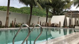 einen Pool mit Palmen und einem Zaun in der Unterkunft SaoConDor Hotel in Con Dao