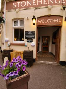 una puerta a una tienda con flores púrpuras en una olla en Stonehenge Inn & Shepherd's Huts en Amesbury