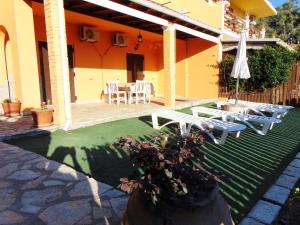 里亞帕德斯的住宿－Maria Apartments - Roumanis，房屋设有带椅子和遮阳伞的庭院