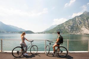 a man and a woman riding bikes by the water at Park Hotel Abbadia in Abbadia Lariana