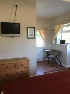 a living room with a dresser and a tv on the wall at Rosemary Cottage in Hooe