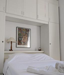 a white bedroom with a white bed and white cabinets at Seafront Apartment Pefkochori in Pefkohori +7 photos