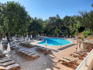 a swimming pool with chaise lounge chairs and umbrellas at Les Restanques - Grimaud in Grimaud