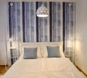 Histrias Apartments Koper في كوبر: غرفة نوم بسرير أبيض وورق جدران أبيض وأزرق