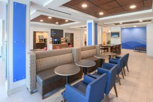 a restaurant with tables and chairs and a couch at Holiday Inn Express Hotel & Suites Richwood - Cincinnati South, an IHG Hotel in Richwood