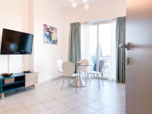 ein Wohnzimmer mit einem Tisch, Stühlen und einem TV in der Unterkunft Taonasi Mazzarò Apartments in Taormina