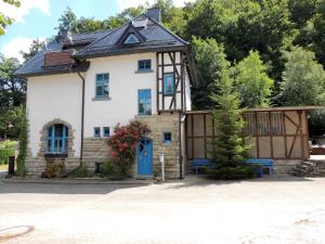 a house with a blue door and trees at Ferienwohnung Bahnhof Wendehausen in Wendehausen