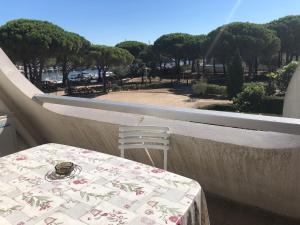 a table and chair on a balcony with a view of a park at Studio 27m2 proche de la plage in Le Grau-du-Roi