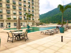 a hotel with a pool and tables and chairs at Lindo Loft Itaipava RJ in Itaipava