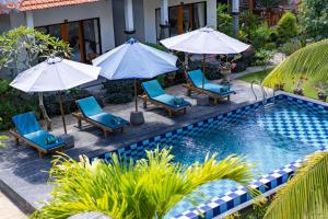 a pool with chairs and umbrellas next to a house at Surya Maha Bungallo in Nusa Penida
