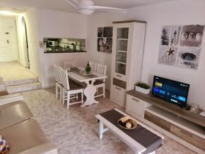 un soggiorno con un tavolo e una televisione di Duplex Parque Santiago 2 close to pool, sea + beach, central, Wifi, heated pool a Playa de las Americas