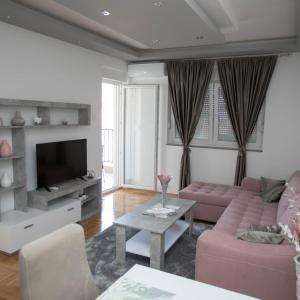 uma sala de estar com um sofá rosa e uma televisão em Oasis of Peace em Trebinje