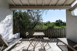 een patio met een tafel en stoelen en een hek bij Le Mas de Cocagne in Saintes-Maries-de-la-Mer