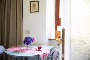 una mesa con un jarrón de flores púrpuras. en La Vigna, en Luino