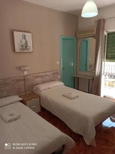 a room with two beds and a mirror at Pensión Duquesa Bed & Breakfast in Granada