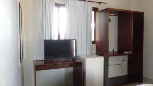 a room with a television on a desk with a window at Bella Natal Praia Hotel in Natal