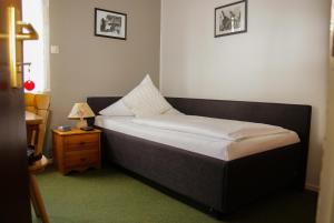 a small bed in a room with a night stand at Hotel Meiendorfer Park in Hamburg