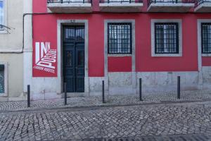 a red and white building with a black door at Inn Possible Lisbon Hostel in Lisbon