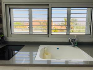 a kitchen counter with a sink and two windows at Perfect Southern Getaway with Balcony in Eilat