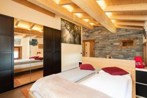 a bedroom with two beds and a stone wall at Hotel Krone in Livigno