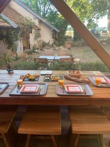 una mesa de madera con platos de comida. en L’allée des peupliers en Chevigny