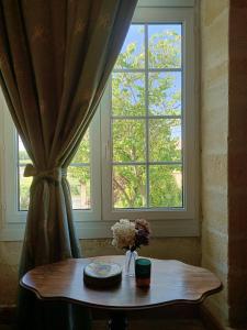 - une table dans une chambre avec une grande fenêtre dans l'établissement Les Logis de Lestiac, à Lestiac-sur-Garonne