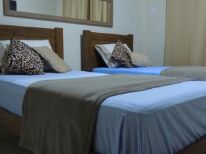 two beds with pillows on them in a room at Quartos Em Casa Caxias - Pousada Paraíso in Duque de Caxias