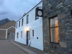 a white building with a clock on the side of it at Gordon House in Tomintoul