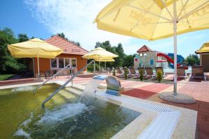 einen Pool mit einer Wasserrutsche und einem Sonnenschirm in der Unterkunft Termál Hotel Vesta in Tápiószecső