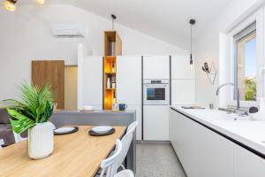a kitchen with a wooden table and white cabinets at Apartment LAURUS in Krk