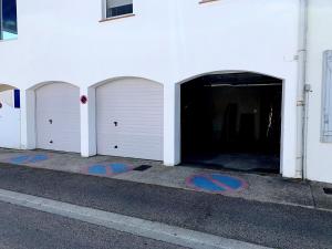 three white garage doors on the side of a building at Hotel Les Palmiers En Camargue in Saintes-Maries-de-la-Mer