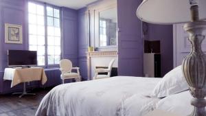una camera da letto con pareti viola, un letto e una scrivania di Le Pan de Bois a Bar-sur-Seine
