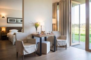 a hotel room with a bed and a table and chairs at La Gree Des Landes - Eco-Hotel-Spa Yves Rocher in Cournon