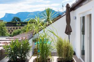 a balcony with plants and an umbrella and mountains at Emma Suite Merano in Merano
