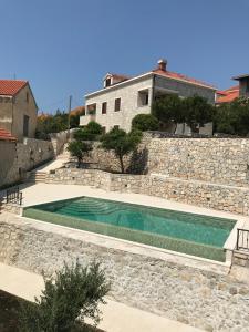 a swimming pool in front of a stone wall at Apartments Kralj Ana in Cavtat