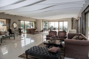 a living room with couches and tables and windows at GARDELLI RESORT in Laganas