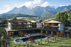 an aerial view of a resort with mountains in the background at Wellness und Brunch Hotel MorgenZeit beheizter Naturteich Genuss Frühstück bis 13 Uhr Hochkönig Sommercard in Maria Alm am Steinernen Meer