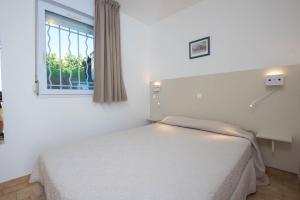 - une chambre blanche avec un lit et une fenêtre dans l'établissement Résidence Arinella, à Lumio