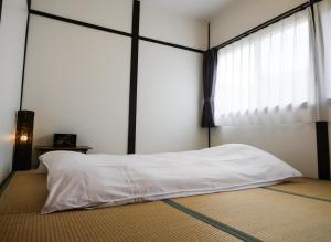 a bedroom with a white bed with a large window at Sennichi House in Kanazawa
